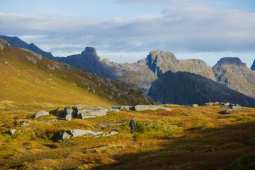 Beautiful Vibrant Norwegian Mountain Landscape from Ryten peak - famous mountain in Lofoten Islands, Moskenes municipality, Nordland with a view of Kvalvika beach, with hiking tourists and blue sky
