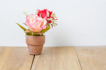plastic flower in pot on wooden board