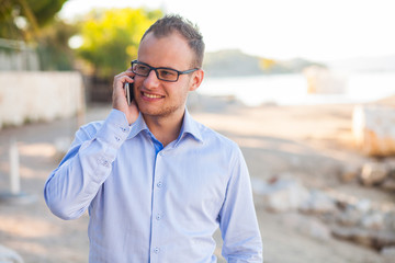 Young tourist in shirt with mobile phone on a Croatian beach. Positive emotions.