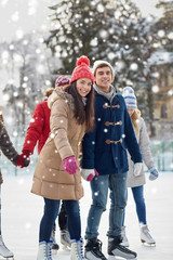 happy friends ice skating on rink outdoors