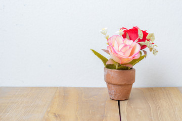 plastic flower in pot on wooden board