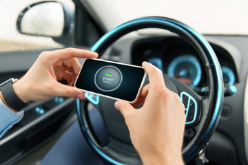 hands with start engine icon on smartphone in car