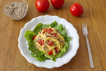 healthy dinner consists of salad and pasta with tomatoes and sunflower seeds