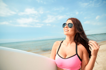 smiling young woman with surfboard on beach