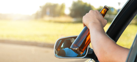 Car driver holding a bottle of beer