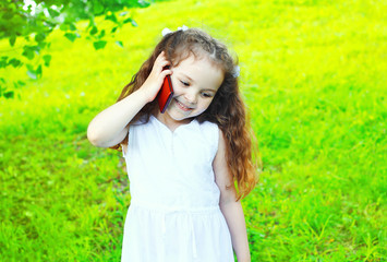 Naklejka na ściany i meble Happy smiling child talking on smartphone in summer day