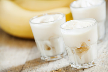 Obraz na płótnie Canvas Fresh homemade banana yogurt in glass on old wooden table, selec