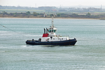 Tugboat towing ship in harbor