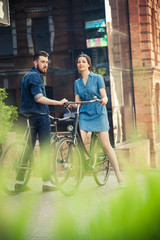 Fototapeta premium Young couple sitting on a bicycle opposite the city 