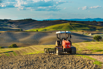 Red tractor on tracks in the landscape of Tuscany and cloudy ski
