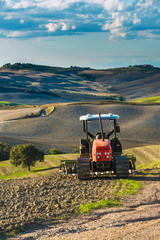 Red tractor on tracks in the landscape of Tuscany and cloudy ski