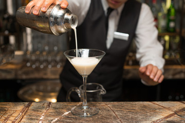Barman at work, preparing cocktails. pouring pina colada to cocktail glass. concept about service and beverages.