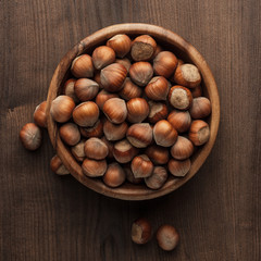 hazelnuts in wooden bowl on the brown table