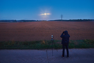 Fotograf beobachtet die Mondfinsternis mit einem Fernglas