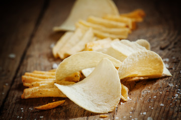 Chips and salt on old wooden table, selective focus