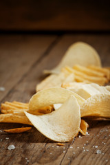 Chips and salt on old wooden table, selective focus