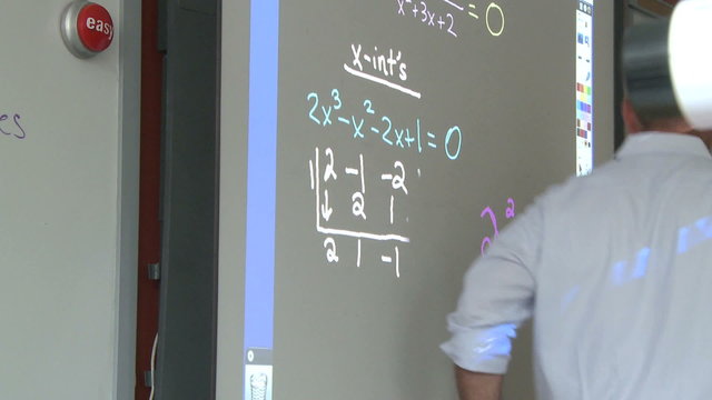 Teacher working on board in front of class