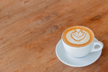 Hot cafe latte with latte art on wooden table