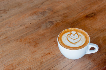 Hot cafe latte with latte art on wooden table