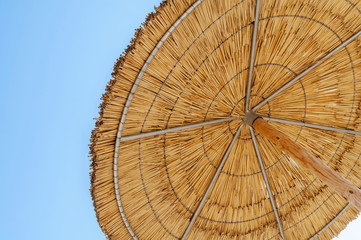 A reed sun umbrella and blue sky symbolizing vacationing in summ