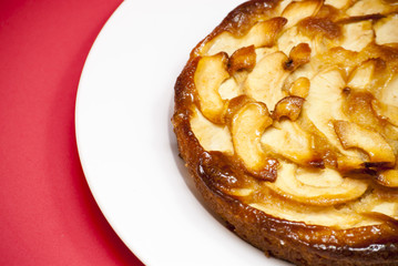 Apple pie on a white plate with red background