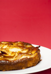 Apple pie on a white plate with red background