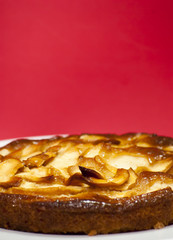 Apple pie on a white plate with red background