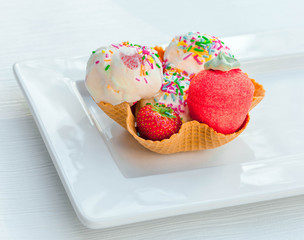 Strawberry ice cream scoops with colorful sprinkles
in waffle bowl