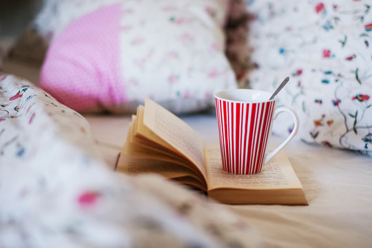 an open book and a mug of tea in bed