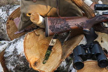 Rifle with hunting knife on the wood