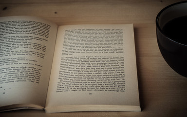 Fototapeta premium reading a book on a wooden table with coffee