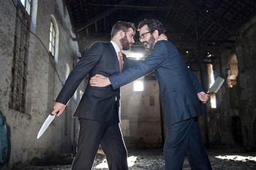 Dos hombres de negocios parecen hacer tratos mientrras esconden cuchillos