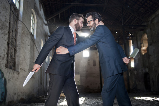 Dos hombres de negocios parecen hacer tratos mientrras esconden cuchillos
