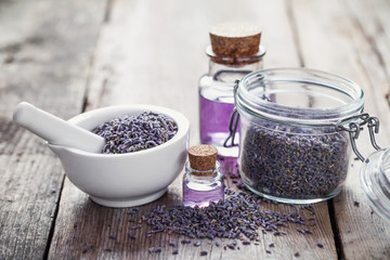 Fototapeta na wymiar Dry lavender flowers in white mortar, glass jar of lavender and