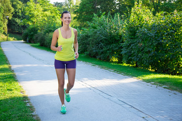 Happy slim jogging woman running in park