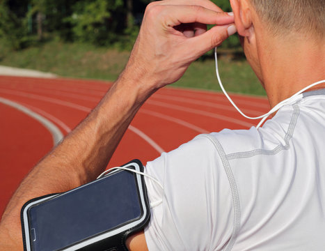Male runner with mobile smart phone, listening to the music during workout. Running, jogging, cardio, sport, active lifestyle concept