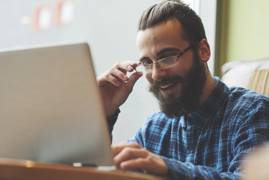 Young Hipster Man Working On Laptop In Coffee Shop