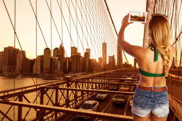 Blond tourist girl taking photo in Brooklyn Bridge