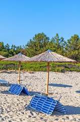 Sunbed, straw umbrella on beautiful Tripiti beach background in