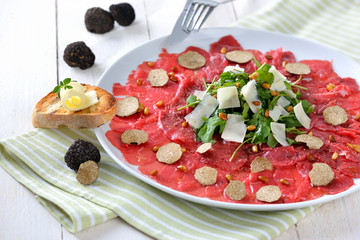 Feines Carpaccio vom Rinderfilet mit schwarzen Herbsttrüffeln und gerösteten Pinienkernen sowie Rucola mit geholbeltem  Parmesan