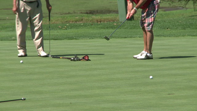 Golfers putting to hole