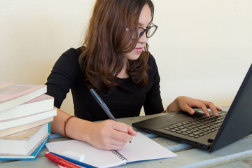 Young woman working, doing homework, with notebook and laptop