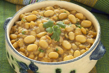 Close up image of Moroccan stewed white beans served in a painted ceramic bowl.
