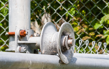 Worn metal roller on fence frame with rusted screw