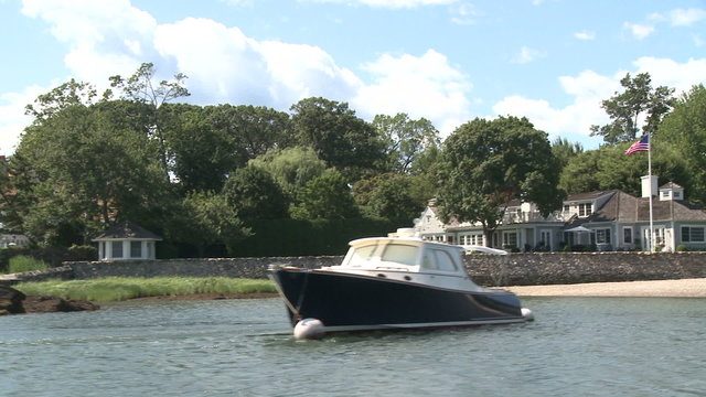 A large home on the water, with a boat docked out front.