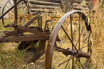 Antique plow with metal wheels in golden grass, Jackson, Wyoming