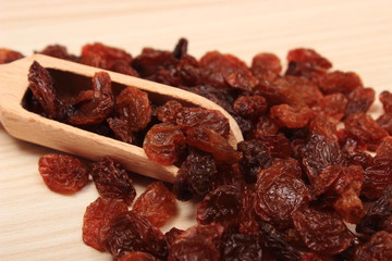 Brown raisins with spoon on wooden table, healthy eating