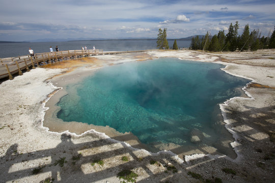 Steaming aqua hot spring, with people on boardwalk, Yellowstone.