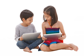 Boy and girl using tablet while sitting on the floor