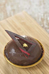 Fresh chocolate dome on wood plate with gold